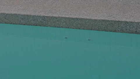 Slow Motion Pan of Pebble Concrete Pool Edge Still Blue Water on Overcast Day Stock Footage 304092270