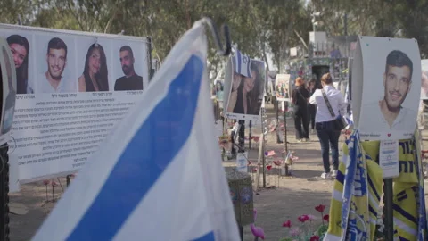 Slow motion pan shot of memorial at the Nova Festival site, posters of victims Stock Footage 297200002