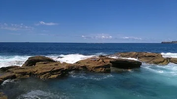 Slow motion pan view of waves hitting clips near Coogee beach, on a sunny sum Stock Footage 86042587