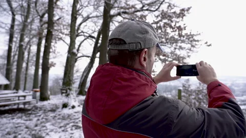 Slow motion panning shot of middle aged man taking video in winter. Stock Footage 147334416