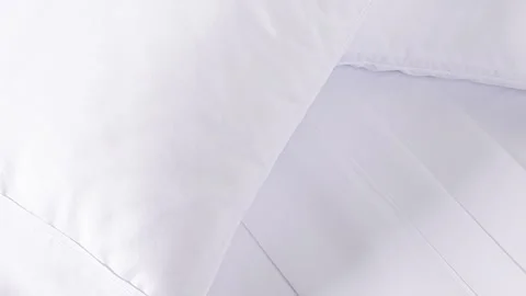 Slow-Motion Panning Shot of White Sheets and Pillows on Bed Stock Footage 313916020