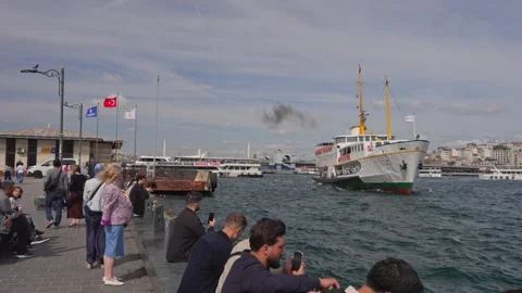 Slow Motion Passenger Ferry Sailing Past Crowded Waterfront Pier at Eminonu Stock Footage 347068311