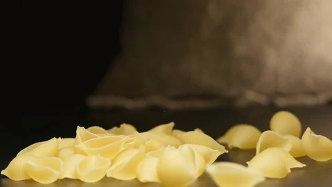 SLOW MOTION: Pasta (conchiglie) fall near a cloth bag Video stock 72495957