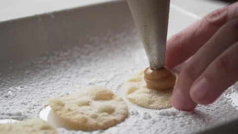 Slow motion of pastry bag tip filling alfajor sheet, close-up Video stock 240942100
