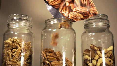 Slow motion: Pecan nuts being poured into a jar. Video stock 90778046