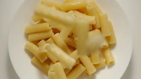 SLOW MOTION: Penne pasta falling into a white plate - Top View Stock Footage 100631779