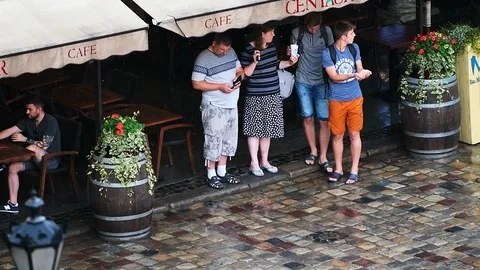 Slow motion of people hiding under restaurant cover in rain, Lviv Ukraine Video stock 112583188