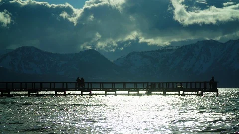 Slow motion people walking on peer on lake with clouds and mountains 動画素材 109260302