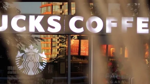 Slow motion of people walking through starbucks store with blurry leaves blowing Stock Footage 83062272