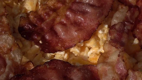 Slow motion of peppering scrambled eggs and sliced crispy wavy bacon close up. Stock Footage 99851937