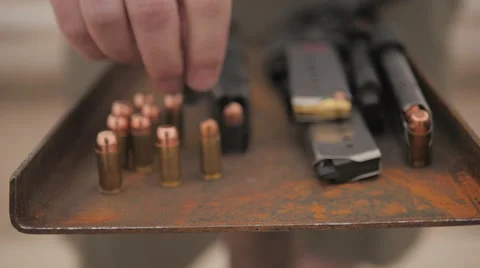 Slow Motion Person Puts Bullet Down Next to Other Ammo Stock Footage 60690564