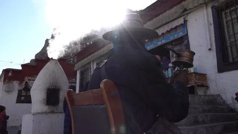 Slow motion pilgrim spinning prayer wheel in Lhasa, sun flare silhouette Stock-Footage 113008250