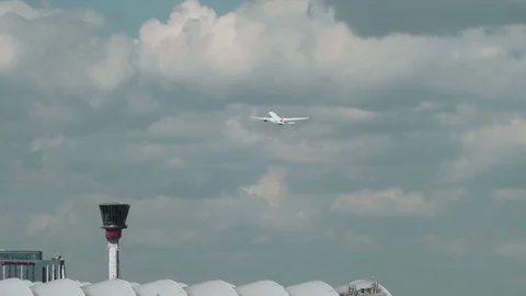 Slow motion plane flies over airport control tower Stock Footage 111912445