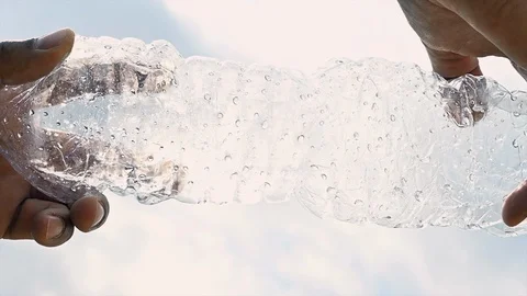 Slow motion of a plastic bottle crushed by the hands of a black man Stock Footage 105824453