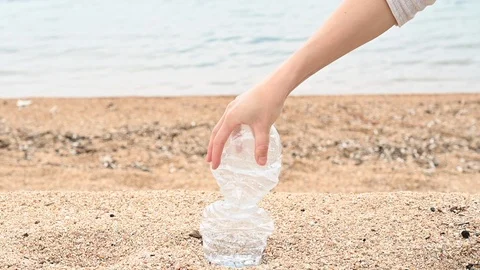 Slow motion of a plastic bottle crushed by the hand of a woman at the beach sea  Vidéo 105857844