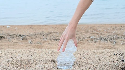Slow motion of a plastic bottle crushed by the hand of a woman at the beach sea Stock Footage 105858571