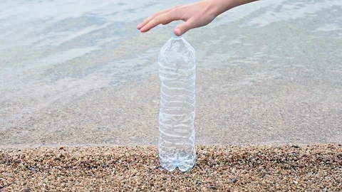 Slow motion of a plastic bottle crushed by the hand of a woman at the beach sea  Stock Footage 105858842