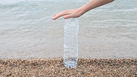 Slow motion of a plastic bottle crushed by the hand of a woman at the beach sea  Stock Footage 105859045