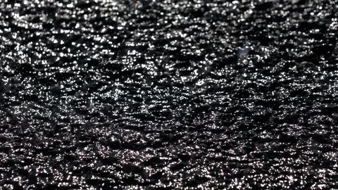 Slow motion of playing sun shine reflection on black water ripple. Vidéo 99143864