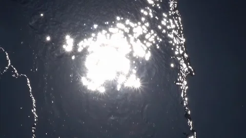 Slow motion of playing water, falling on blue cloudless sky backdrop with sun. Stock Footage 100236095