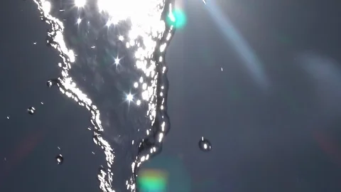 Slow motion of playing water, falling on blue sky backdrop with lens flare. Stock Footage 100237480