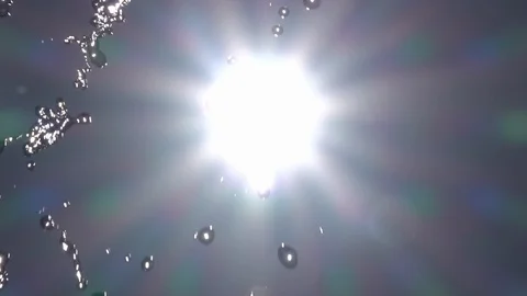Slow motion of playing water on sky backdrop with shining sun and lens flare. Stock Footage 100237520