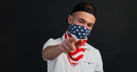 Slow motion portrait of aggressive young protester male hides face behind scarf Stock Footage 120702638