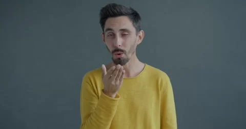 Slow motion portrait of charming guy sending air kiss and winking looking at Stock Footage 255117440