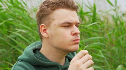 Slow motion portrait close up of a Young man who eats tortilla chips outside Stock Footage 91230854