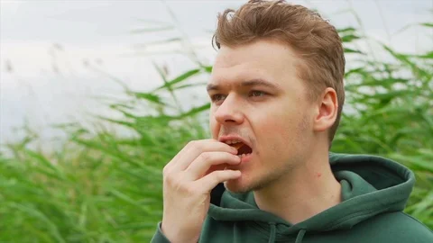 Slow motion portrait close up of a Young man who eats tortilla chips outside Stock Footage 91230871