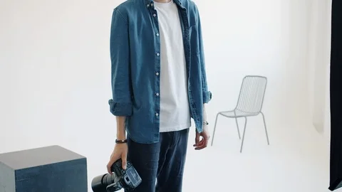 Slow motion portrait of handsome man photographer holding camera in studio Vídeo Stock 124414631
