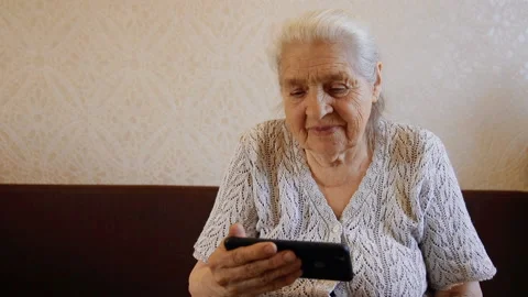 Slow motion portrait of happy is an elderly woman using smartphone and smiling. Stock Footage 89405770