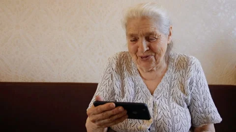 Slow motion portrait of happy elderly woman talking by video link on smartphone Stock Footage 89405976