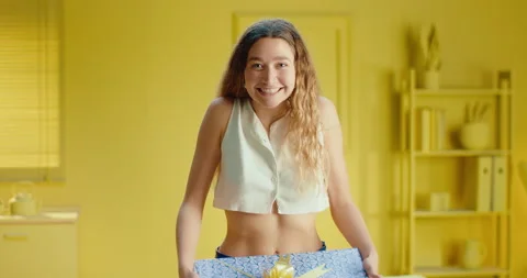 Slow motion of a portrait of a happy pretty young woman holding a gift box and Video stock 188086366
