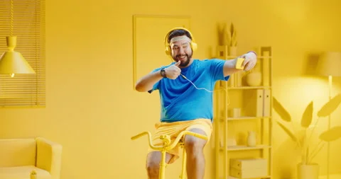 Slow motion portrait of young man riding exercise bike while taking selfie Video stock 165868495