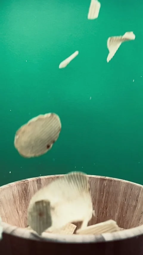 Slow motion of potato chips falling into a wooden bowl, vertical Stock Footage 345154796