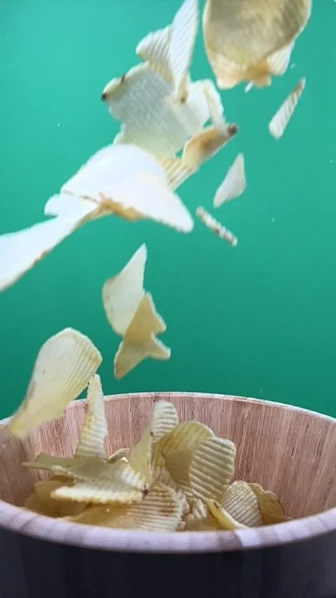 Slow motion of potato chips falling into a wooden bowl, vertical Stock Footage 345154809