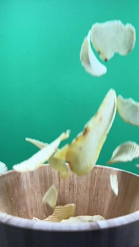 Slow motion of potato chips falling into a wooden bowl, vertical Stock Footage 345154817