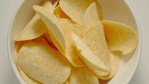 SLOW MOTION: Potato crisps falling into a white bowl - Top View Stock Footage 100430392