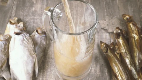 Slow motion pour beer in a mug and salted fish on the table top view Stock Footage 94122482