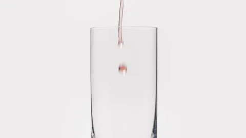 Slow motion pour cherry beer into glass over white background top part Stock Footage