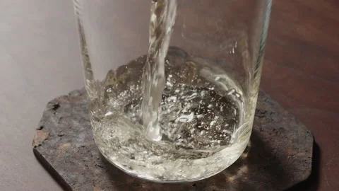 Slow motion pour ginger ale in tumbler glass on walnut table Stock Footage 163593609