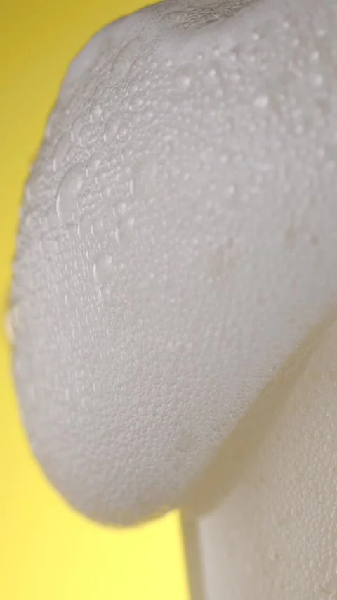 Slow motion pouring beer with foam and bubbles on a yellow background Stock Footage 340482490