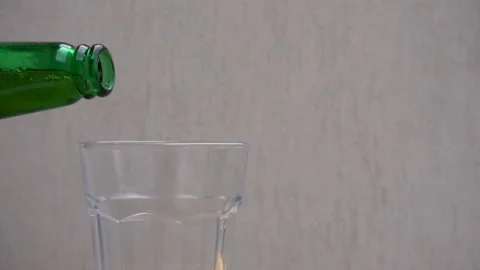 Slow motion pouring beer from the neck of a bottle into a glass Stock-Footage 119757616