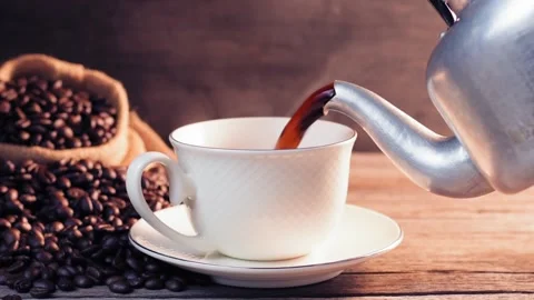 Slow motion pouring black coffee into a white coffee cup with hot steam  Stock Footage 202195090