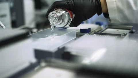 SLOW MOTION pouring a clear liquid into a scientific machine to look for a cure Stock Footage 127533342