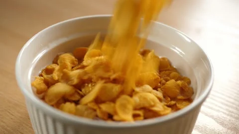 Slow motion pouring cornflakes cereals into a white bowl full of milk Stock Footage 294696520