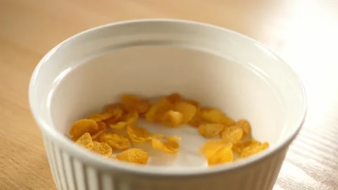 Slow motion pouring cornflakes into an empty white bowl Stock Footage 294696398