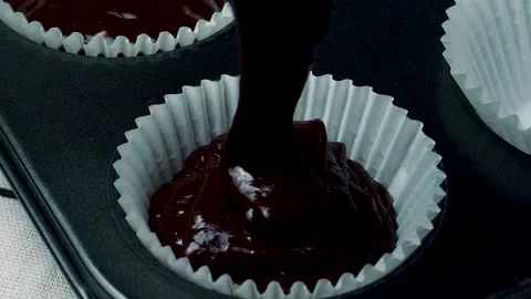 Slow Motion Pouring Cupcake Batter into Paper Liners Stock Footage 306431155
