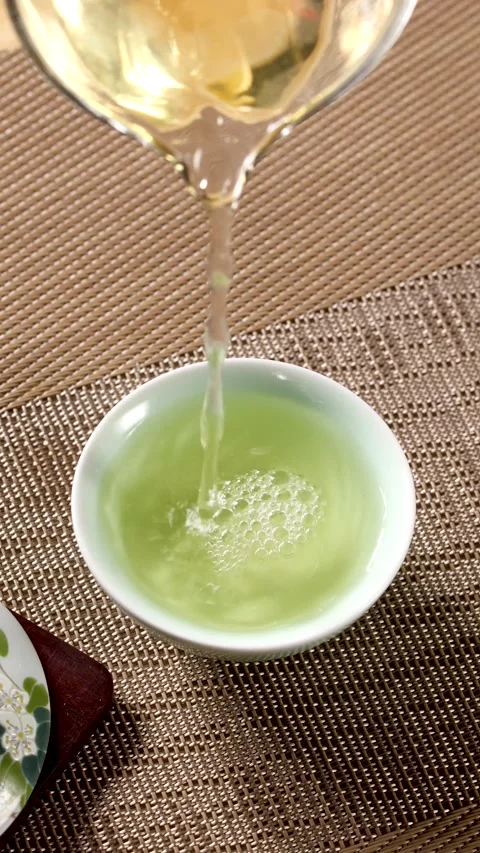 Slow Motion Pouring Green Tea into Ceramic Cup on Bamboo Mat Stock Footage 340006200